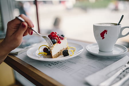 Woman Enjoying Cheese Cake and a Coffee with Fruits in a Cafeteria thumbnail