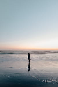 Woman Wades In Ocean At Sunset Photo thumbnail