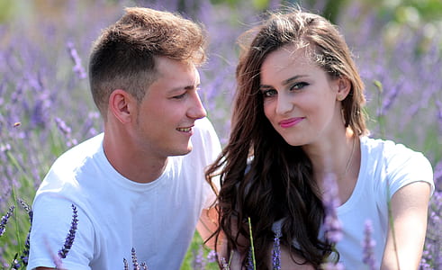 man and woman sitting on field of purple petaled flowers thumbnail