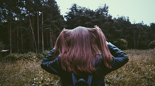 Woman in Black Leather Jacket Standing Before Green Leaved Trees thumbnail