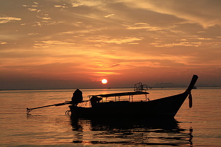 silhouette of boat under orange sunsedt thumbnail