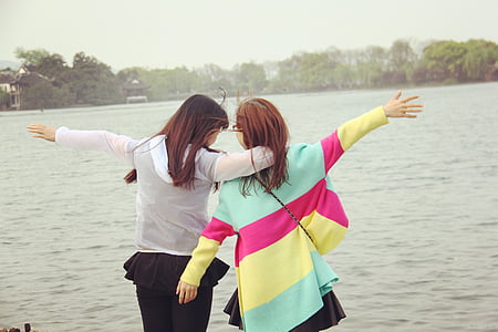 two person spreading arms with body of water background thumbnail