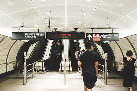 man wearing black t-shirt and black shorts outfit facing escalator thumbnail