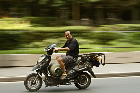 man on motor scooter on road thumbnail