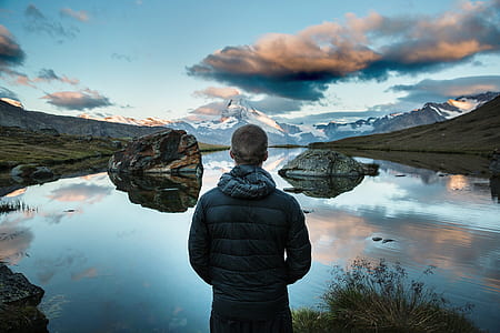 man in black jacket standing in front of body of water during daytime thumbnail