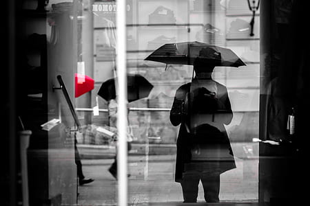 reflection of people walking on street while holding umbrella thumbnail