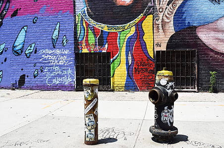 black fire hydrant on sidewalk perpendicular to mural wall thumbnail