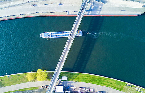 top view photography of boat on body of water under bridge thumbnail