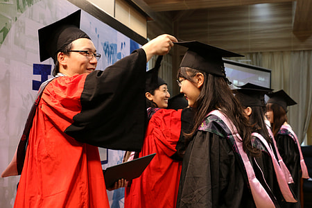man in red and black graduation gown giving a certificate to a girl thumbnail