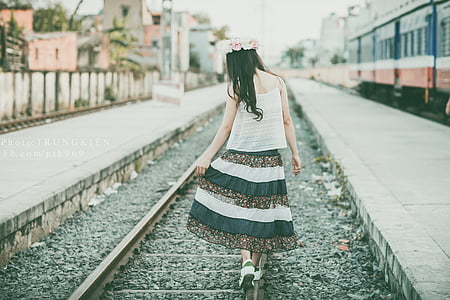 woman wearing white and black dress walking on train rail thumbnail