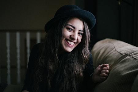 woman in black hat seating on beige couch thumbnail