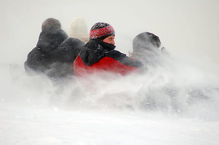 four people sliding on ground covered with snow thumbnail