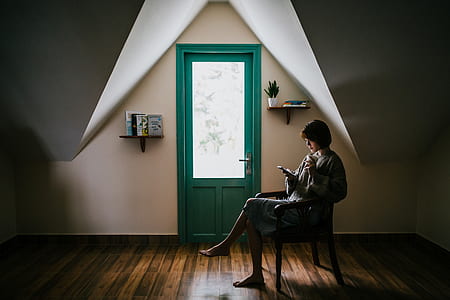 person sitting on chair using phone near door thumbnail