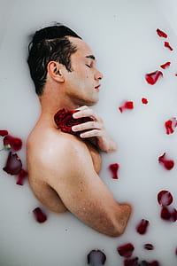 man lying on milk bath with red petals thumbnail