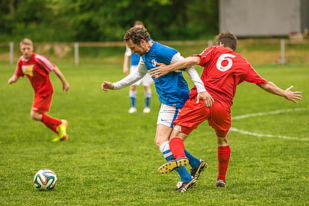 four men playing soccer during daytime thumbnail