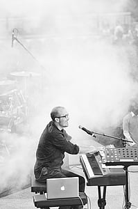 grayscale photo of man singing while playing electronic keyboard thumbnail