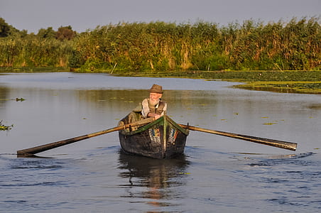 man rowing a boat in middle of calm body of water thumbnail