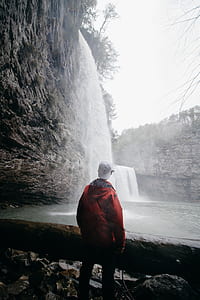 man standing on rock facing waterfall thumbnail