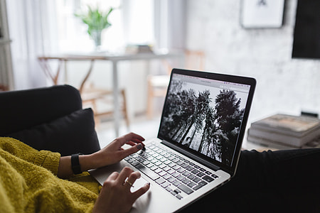 Young woman sitting on the sofa and working on her laptop thumbnail