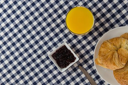 Overhead shot of orange juice drink, croissants and jam thumbnail