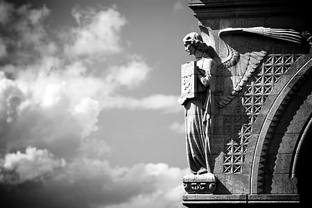 greyscale photo of angel statue sculpted on building thumbnail