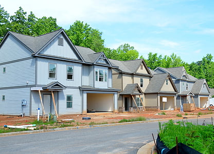 houses beside trees under cloudy sky during daytime thumbnail