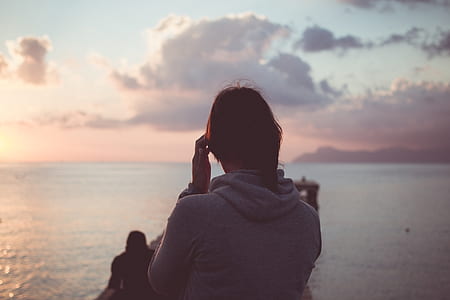 woman in front brown wooden dock under gray cloudy sky thumbnail