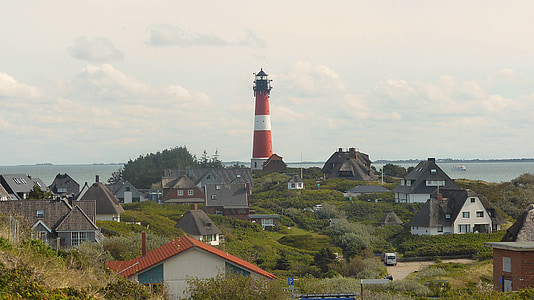 red and white lighthouse near houses during daytime thumbnail