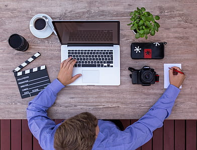 person writing on paper with MacBook Pro on table thumbnail