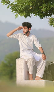 man sitting down beside green leafed tree thumbnail