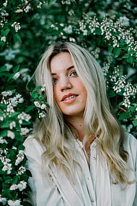 woman in white button-up shirt with grey hair near white flowers smiling thumbnail