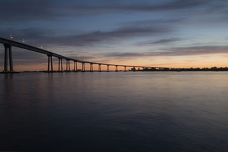 concrete bridge over body of water during sunset thumbnail