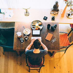 person clicking on white wireless keyboard on brown wooden table with fruits and cups thumbnail