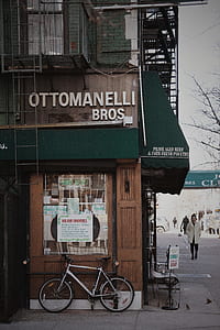 white city bike leaning against Ottomanelli Bros building at daytime thumbnail