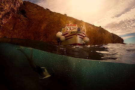 woman diving on ocean with boat on top thumbnail