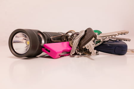 several gray keys on keychain beside black flashlight thumbnail