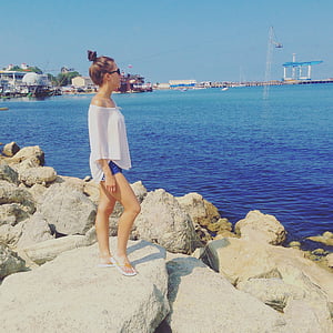 woman standing on rock facing through ocean during daytime thumbnail