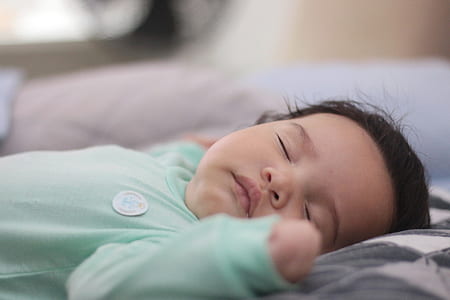 baby sleeping on gray and white mattress thumbnail