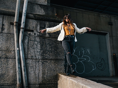 woman in white cardigan standing on gray concrete bridge thumbnail