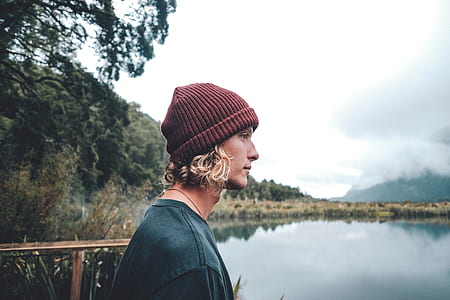 selective focus photography of man beside lake between forest thumbnail