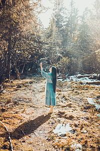 woman standing on field pointing left hand upward during daytime thumbnail