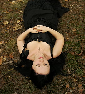 woman in black sleeveless dress lying on brown and green grasses thumbnail