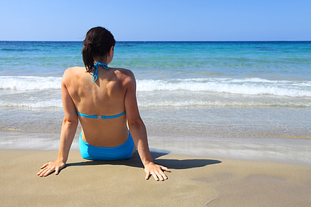 woman wearing blue bikini sitting on seashore thumbnail