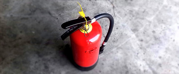 selective focus photography of red and black fire extinguisher on gray concrete surface thumbnail