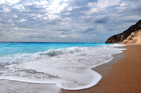 landscape photography of beach under cloudy sky during daytime thumbnail
