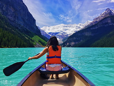 woman wearing personal flotation device sitting on boat while holding boat paddle thumbnail