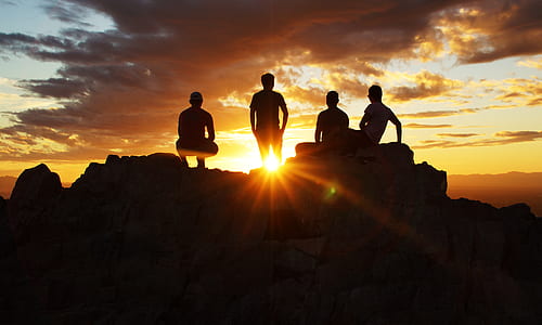 four people on rock looking at sun thumbnail