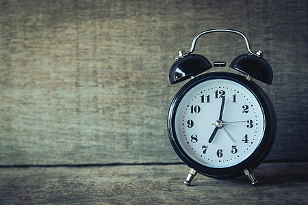 round black and white analog alarm clock on brown wooden rack thumbnail