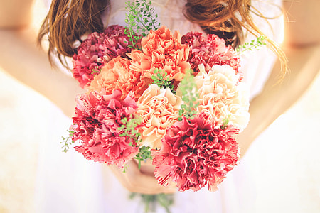 woman wearing , white bridal wedding dress, holding, orange, red,and pink flower bouquet thumbnail