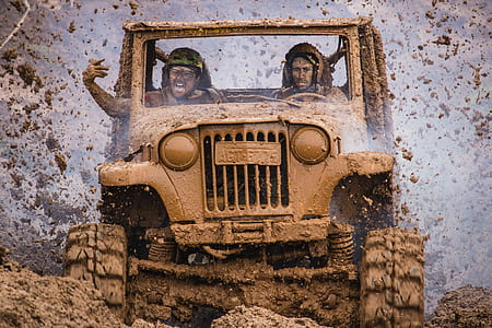 two men riding on mud covered wrangler during daytime thumbnail